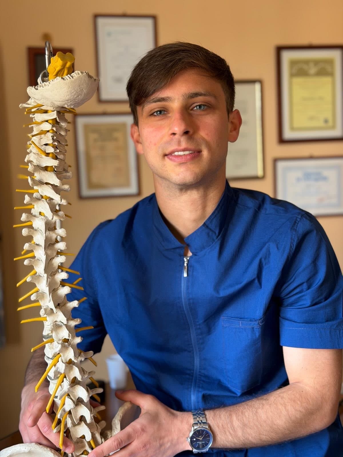 Luca Lombardi nel suo studio osteopatico con un modello anatomico della colonna vertebrale